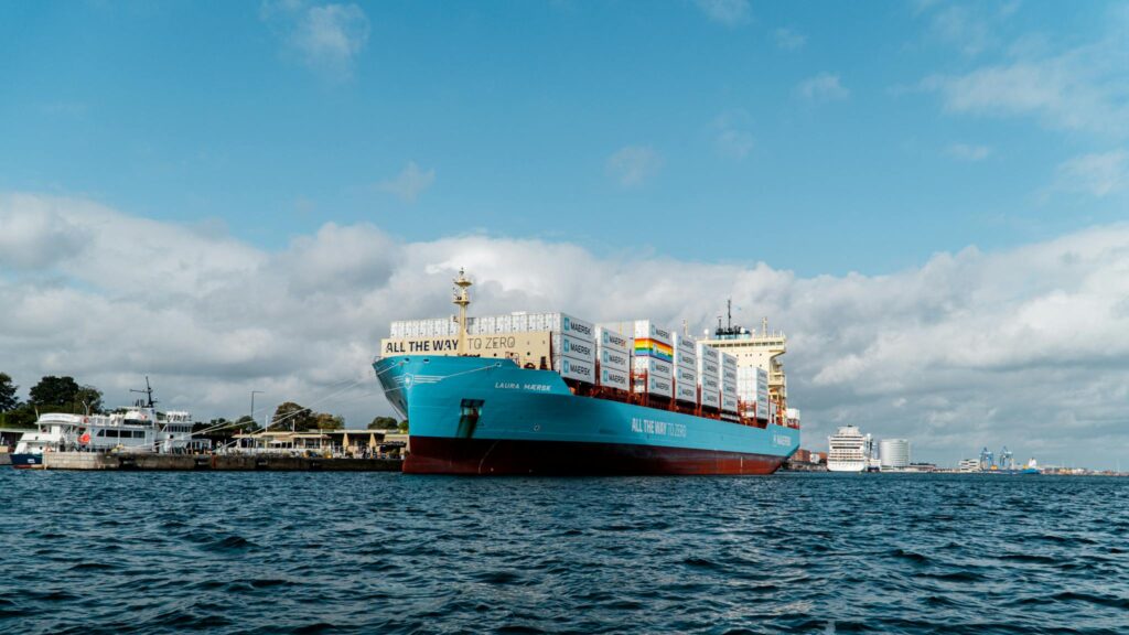 A Maersk container ship in Copenhagen harbor under a bright blue sky.